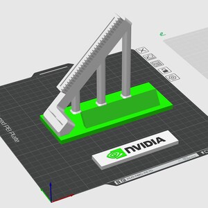 May include: A 3D printed model of a structure with a ramp and three pillars. The model is printed in gray and green plastic and is sitting on a black and gray grid surface. The model is labeled with the NVIDIA logo.