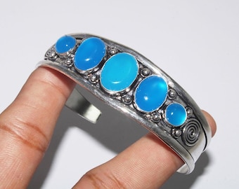 May include: Silver bracelet with five oval blue gemstones set in a decorative silver band.