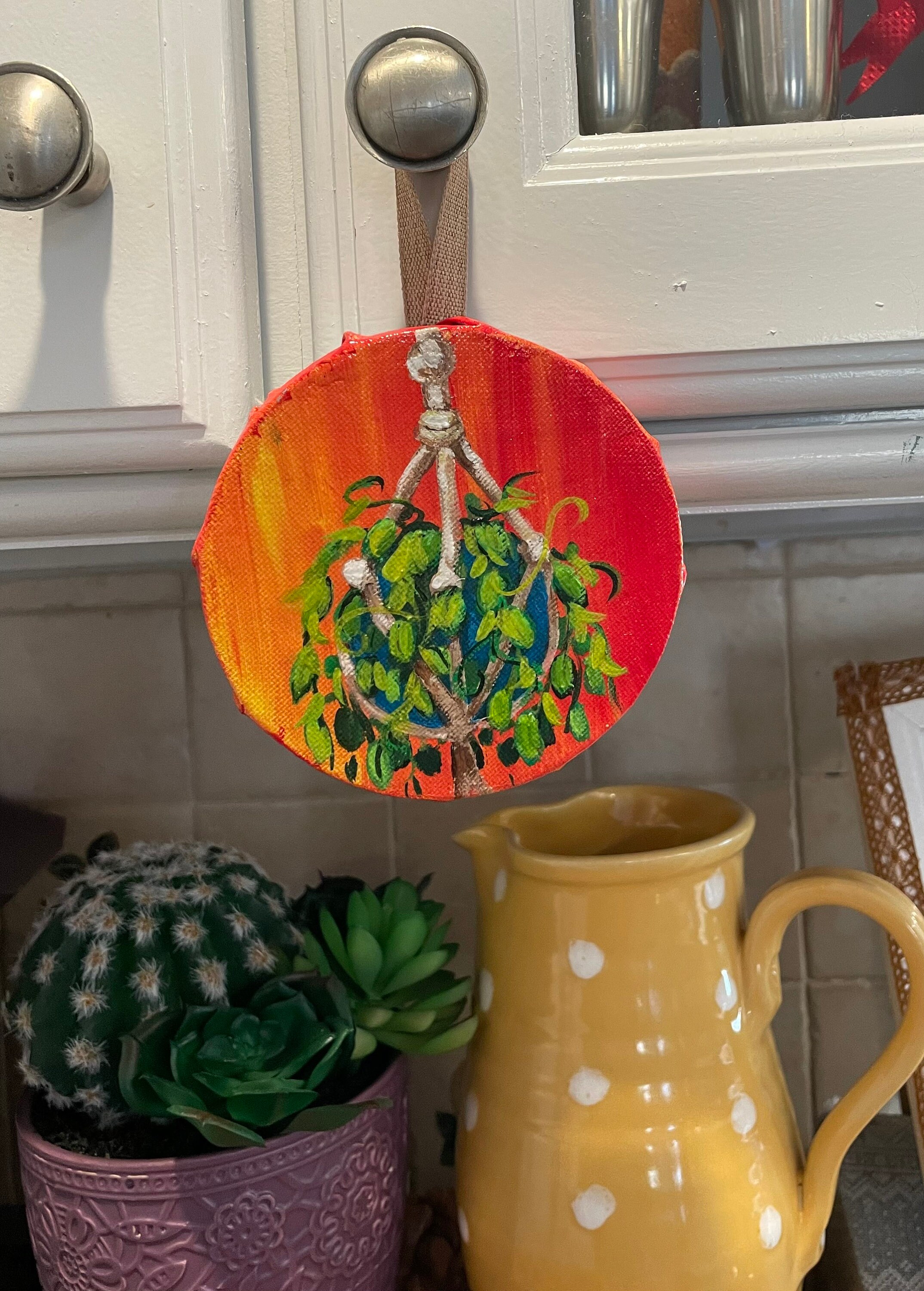 painted hanging plant on round canvas with red and orange  background