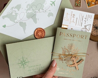 May include: A green and gold passport-style wedding invitation with a compass, airplane, and world map design. The text reads "Love is in the air" and "August 12, 2023".