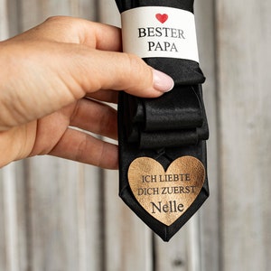 May include: Black tie with a white tag that says "Best Dad" with a red heart and a gold heart-shaped tag that says "I loved you first, Nelle".