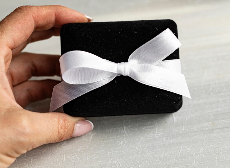 May include: A black velvet gift box with a white satin ribbon tied in a bow.