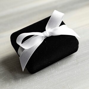 May include: A black velvet gift box with a white satin ribbon tied in a bow.