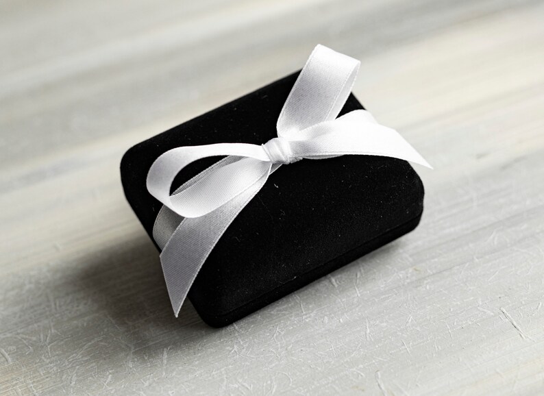 May include: A black velvet gift box with a white satin ribbon tied in a bow.
