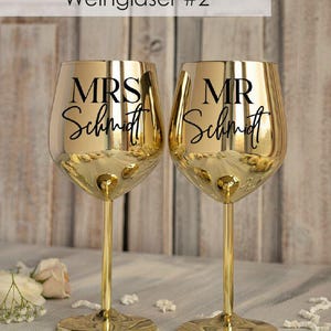 May include: Two gold-colored wine glasses with black lettering. The glass on the left says "MRS Schmidt" and the glass on the right says "MR Schmidt".