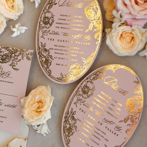 May include: A pink oval wedding invitation with gold foil lettering and floral designs. The invitation reads "Details" and includes the wedding ceremony and reception information. The text reads "Please join us for dinner and dancing immediately following the wedding ceremony under the right sky. The Garden Valley. The Garden Valley Pond, Free Love Old Oakwoods Sta. 1939 Petaluma, California. At Seven O'Clock. Black Tie."