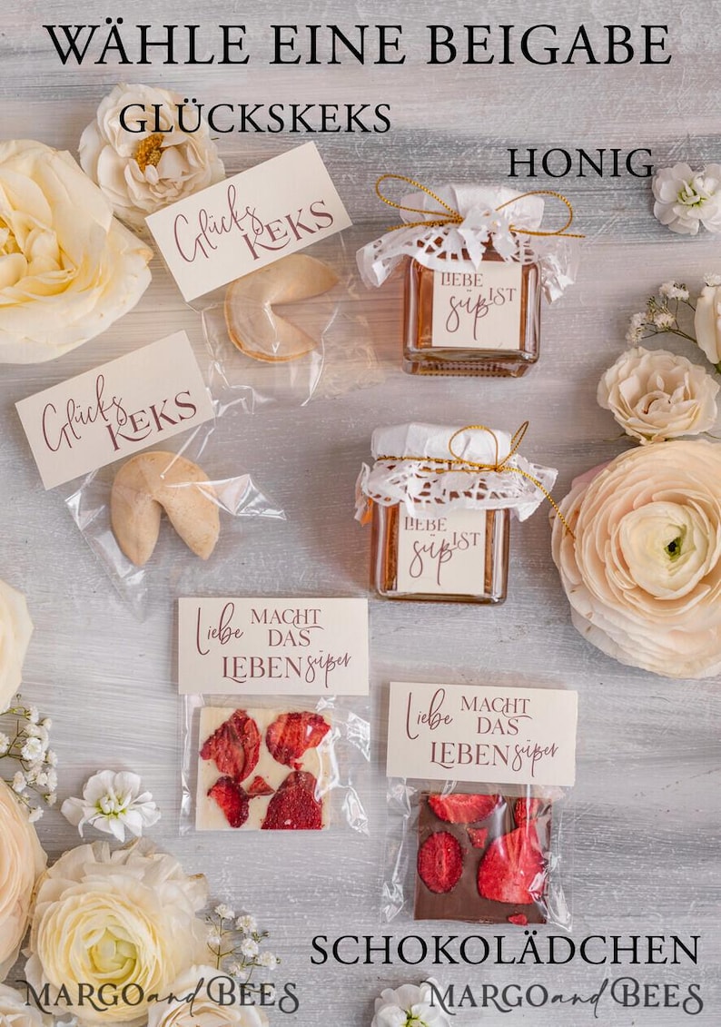 May include: A selection of wedding favors displayed on a wooden surface. The favors include fortune cookies, honey jars, and chocolate bars. The fortune cookies are wrapped in clear plastic bags with a tag that says "Gl&uuml;ck's Kek's". The honey jars are decorated with lace and a tag that says "Liebe Macht Das Leben S&uuml;per". The chocolate bars are wrapped in clear plastic bags with a tag that says "Liebe Macht Das Leben S&uuml;per".