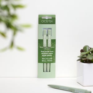 May include: Two green ballpoint pens in a plastic package. The package is green and has the text "OCESIN" and "Sustainable stationery with style. Pens made from recycled ocean waste plastic. RECYCLED BALL PENS" printed on it.