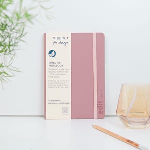 May include: A pink lined A5 notebook with a recycled leather cover. The notebook is made from 100% sustainable lined paper. The cover has the text "VENT for change" and "edit (edit)" printed on it. The notebook is part of a sustainable stationery line.