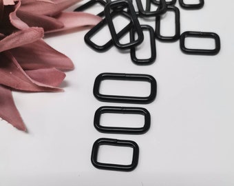 Peut inclure: Un ensemble de quatre anneaux en D en métal noir de différentes tailles. Les anneaux sont disposés verticalement du plus grand au plus petit.