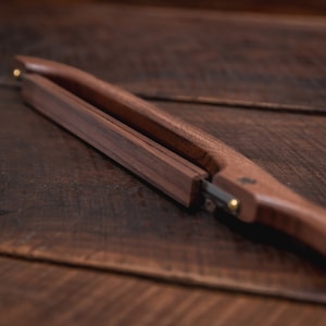May include: A pair of wooden tongs with a brass accent. The tongs are made of dark wood and have a simple design.