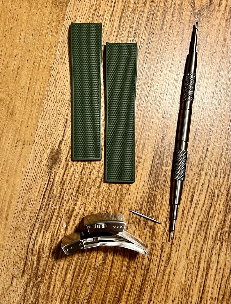 Puede incluir: Dos correas de reloj verde oscuro con superficie texturizada, una correa de reloj plateada con un bot&oacute;n de liberaci&oacute;n y una herramienta plateada para quitar las correas de reloj.