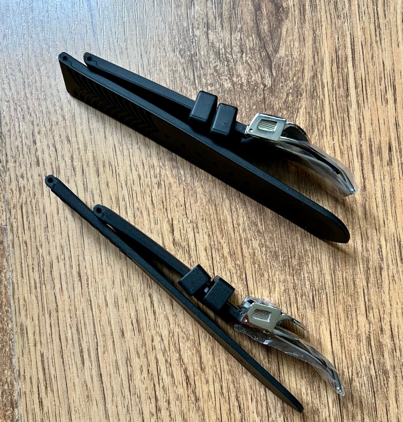 Puede incluir: Dos correas de reloj negras con hebillas plateadas. Las correas est&aacute;n hechas de un material similar al caucho y tienen una superficie texturizada.