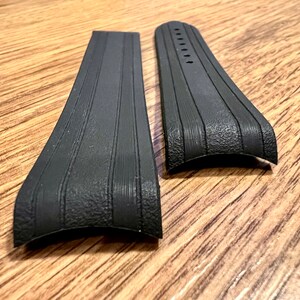 Puede incluir: Dos correas de reloj de goma negra con una superficie texturizada y un dise&ntilde;o acanalado.