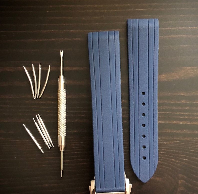 Puede incluir: Dos correas de reloj de silicona azul con una herramienta de correa de reloj plateada y pasadores de resorte.