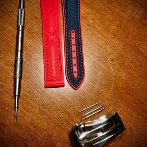Puede incluir: Kit de reemplazo de correa de reloj con una correa roja y azul marino, una herramienta plateada, pasadores plateados y un cierre plateado. La correa roja tiene un dise&ntilde;o texturizado. La correa azul marino tiene costuras rojas.
