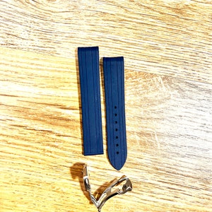 Puede incluir: Dos correas de reloj de caucho azul oscuro con una hebilla plateada. Las correas tienen una superficie texturizada y est&aacute;n dise&ntilde;adas para un reloj.