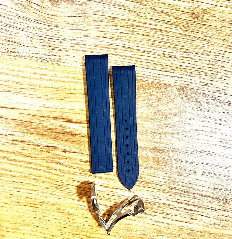 Puede incluir: Dos correas de reloj de caucho azul oscuro con una hebilla plateada. Las correas tienen una superficie texturizada y est&aacute;n dise&ntilde;adas para un reloj.