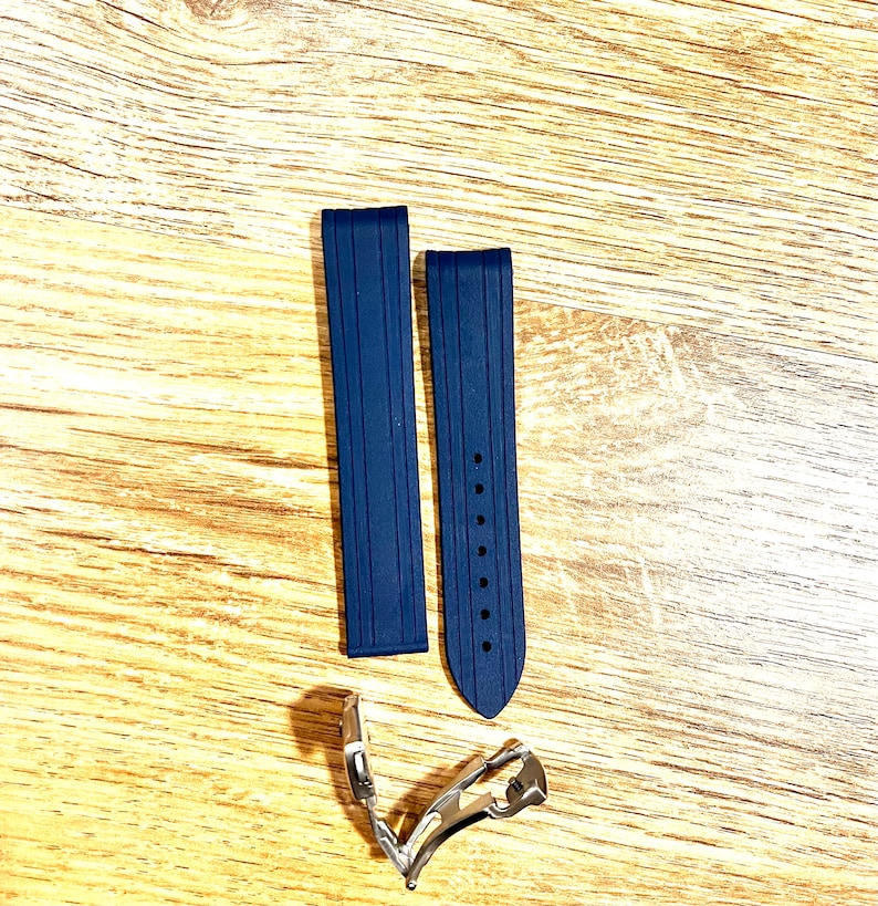 Puede incluir: Dos correas de reloj de caucho azul oscuro con una hebilla plateada. Las correas tienen una superficie texturizada y est&aacute;n dise&ntilde;adas para un reloj.