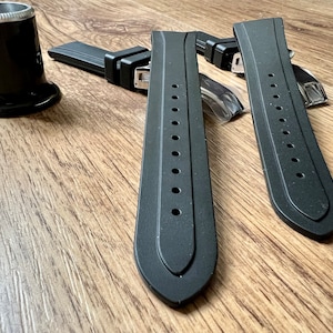 Puede incluir: Dos correas de reloj de caucho negro con herrajes met&aacute;licos. Las correas tienen una superficie texturizada y est&aacute;n dise&ntilde;adas para un reloj.