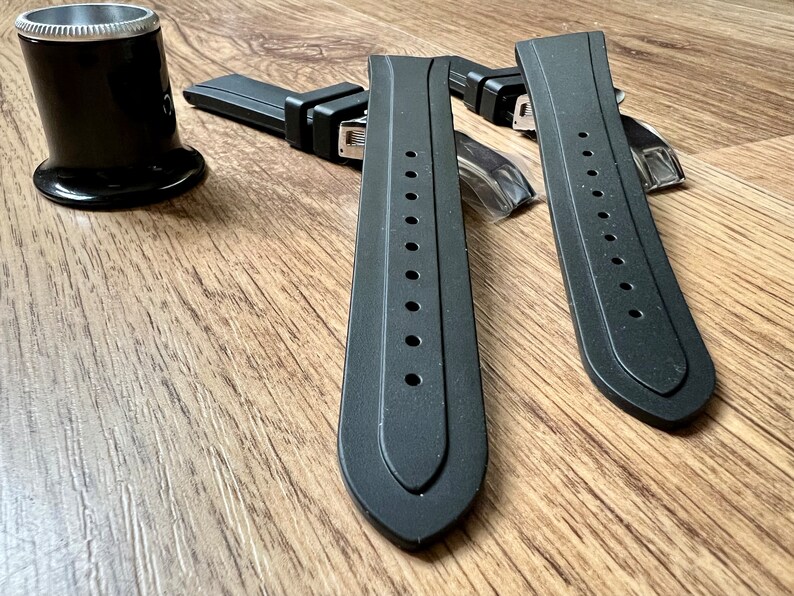 Puede incluir: Dos correas de reloj de caucho negro con herrajes met&aacute;licos. Las correas tienen una superficie texturizada y est&aacute;n dise&ntilde;adas para un reloj.