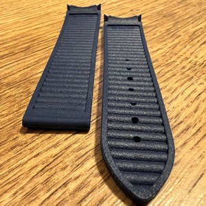 Puede incluir: Dos correas de reloj azul oscuro con una superficie texturizada. Las correas est&aacute;n hechas de un material similar al caucho.