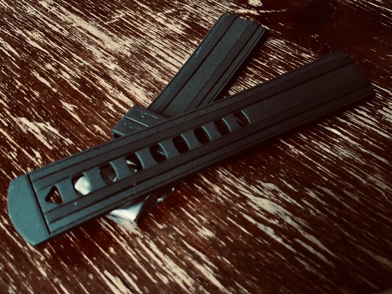 May include: Two black watch bands with a textured surface and a row of holes. The bands are made of rubber.