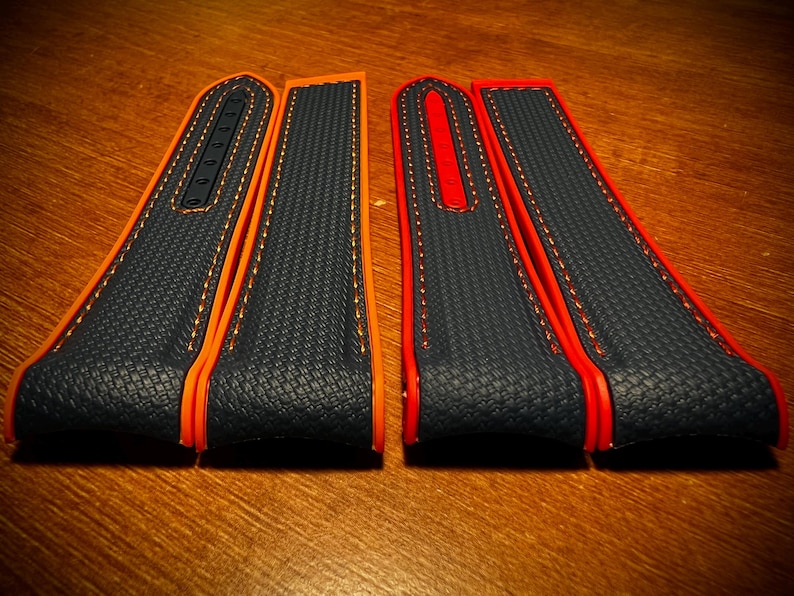 Puede incluir: Dos correas de reloj con una superficie azul marino texturizada, bordes naranjas y rojos y costuras en contraste. Las correas est&aacute;n hechas de un material duradero y est&aacute;n dise&ntilde;adas para un ajuste c&oacute;modo. Un accesorio elegante.