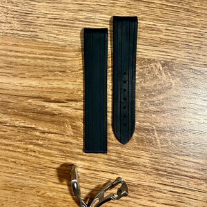 Puede incluir: Dos correas de reloj de caucho negro con una hebilla plateada. Las correas tienen una superficie texturizada y est&aacute;n dise&ntilde;adas para un reloj.