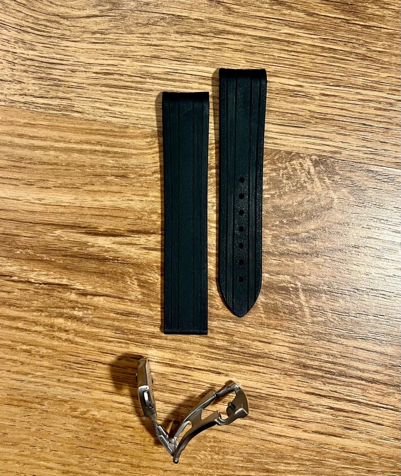 Puede incluir: Dos correas de reloj de caucho negro con una hebilla plateada. Las correas tienen una superficie texturizada y est&aacute;n dise&ntilde;adas para un reloj.