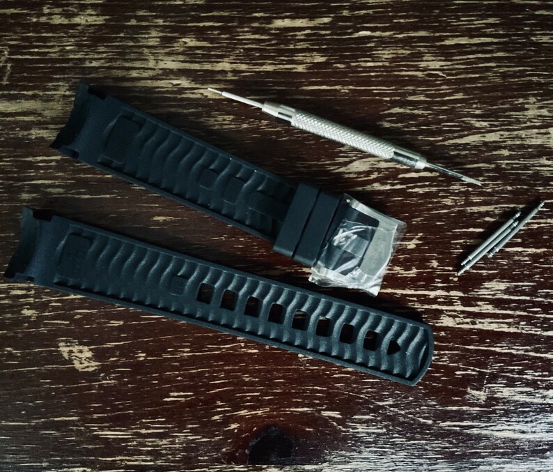 May include: Two black watch bands with a silver tool for adjusting the bands.
