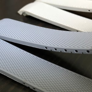 Puede incluir: Dos correas de reloj grises con una superficie texturizada y peque&ntilde;os agujeros a lo largo del borde.