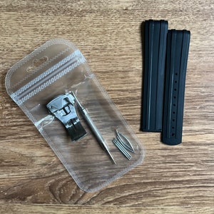 Puede incluir: Un juego de correas de reloj negras con una herramienta de barra de resorte plateada y barras de resorte en una bolsa de pl&aacute;stico transparente.