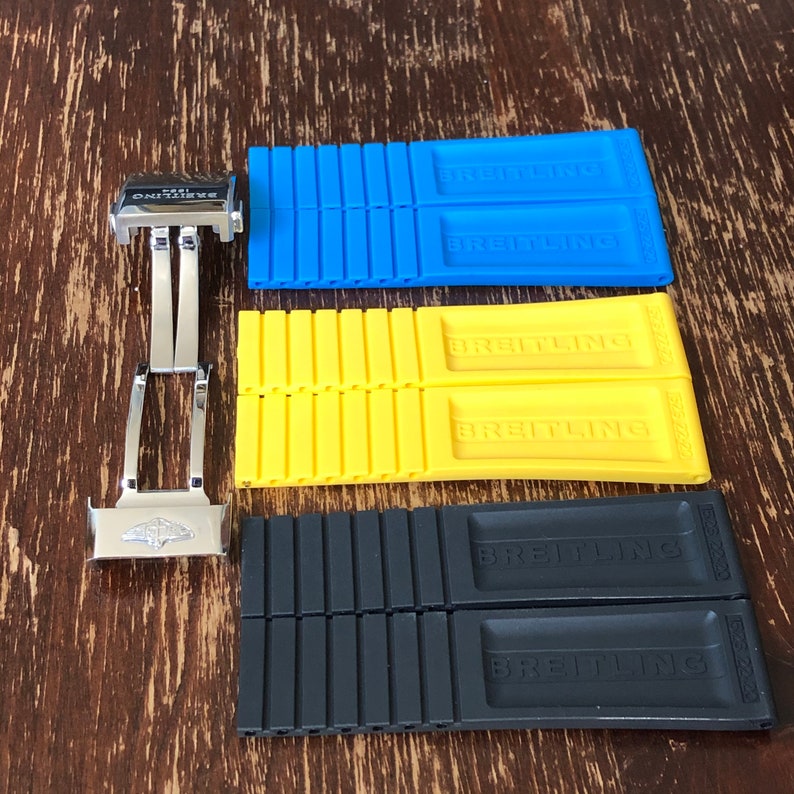 May include: Three watch strap spring bar tools, one blue, one yellow, and one black. Each tool has the word "Breitling" printed on it.