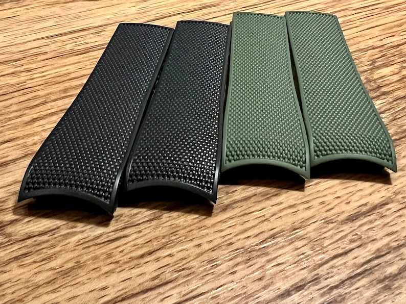 Puede incluir: Cuatro correas de reloj, dos negras y dos verdes, con una superficie texturizada.