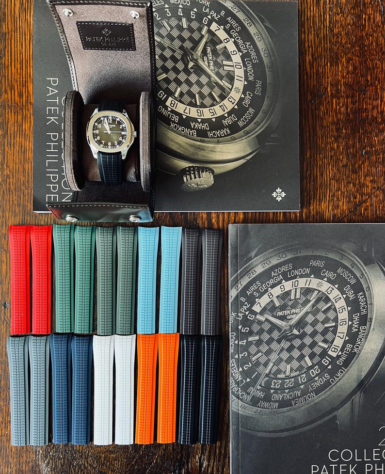 May include: A high-end wristwatch with a black strap is presented in a leather case, with a selection of vibrant watch straps. The watch features a silver dial and is shown with a book bearing the words "Patek Philippe".