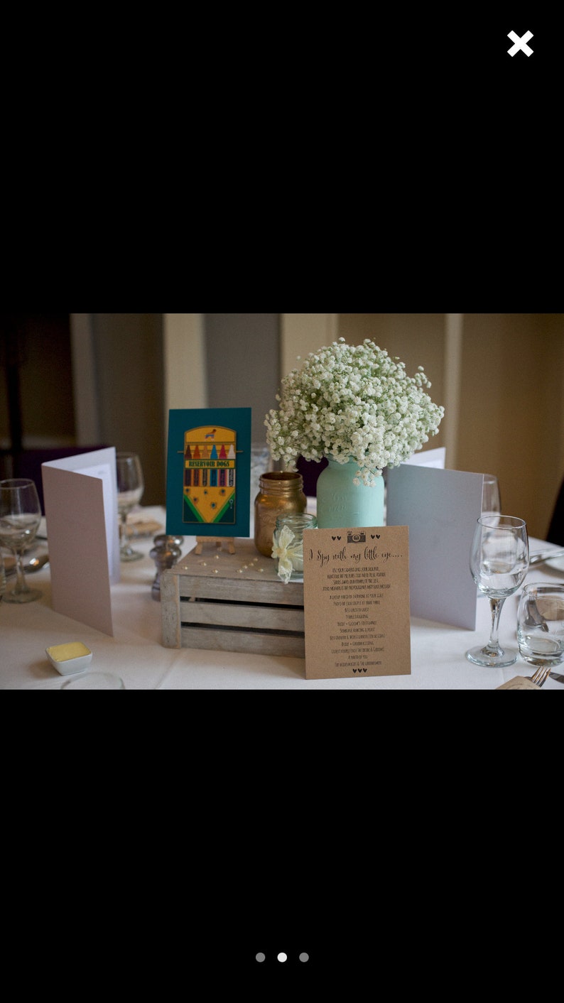 May include: A wedding table centerpiece with a rustic wooden crate, a teal mason jar filled with white baby's breath, and a sign that reads "I Do with my little one..."