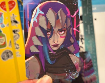 May include: A sticker featuring a digital illustration of a woman with purple hair and a pink and gray hooded jacket. The woman has a fierce expression and is wearing a black choker. The background is a dark blue and purple gradient with white and pink accents.