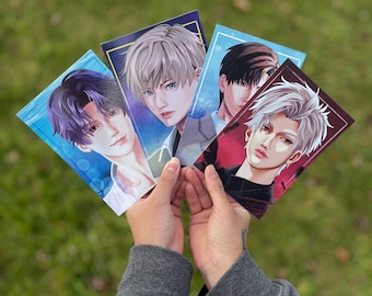 May include: Four illustrated cards featuring anime-style portraits of men with different hair colors and styles. The cards are held in a person's hands against a green grassy background.