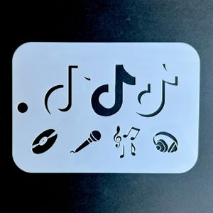 May include: White plastic stencil with various music-themed cutouts, including a record, microphone, musical notes, and the TikTok logo.