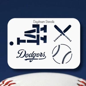 May include: White stencil with the words "Daydream Stencil" at the top. The stencil features a baseball, two crossed bats, the word "Dodgers", and a stylized "LA" logo.