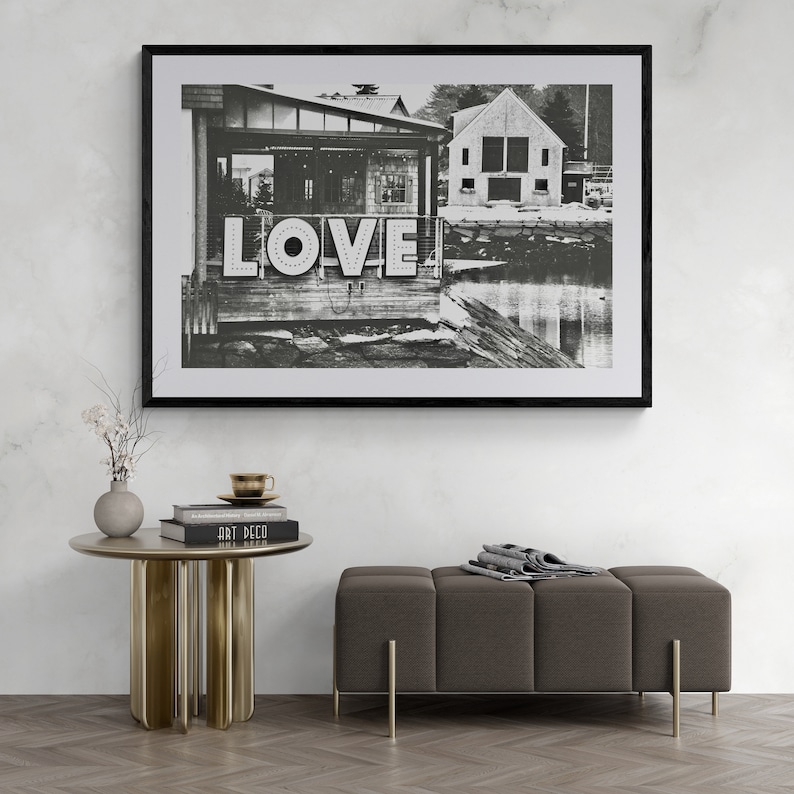 May include: Black and white photograph of a building with the word "LOVE" in large letters on the side. The building is located on a waterfront with a small boat dock in the foreground.