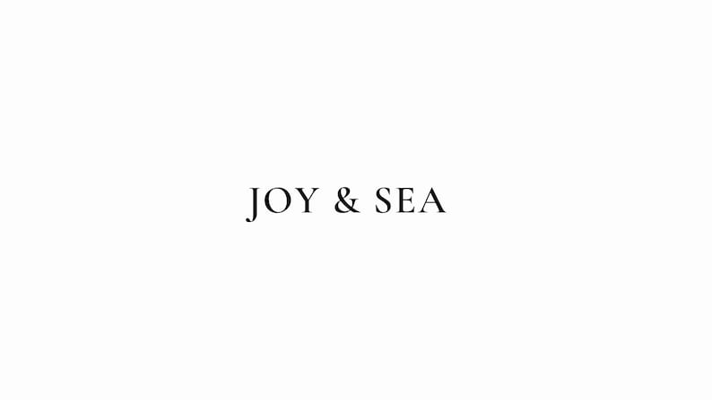 May include: A simple logo design with the text "JOY & SEA" in black font on a white background.
