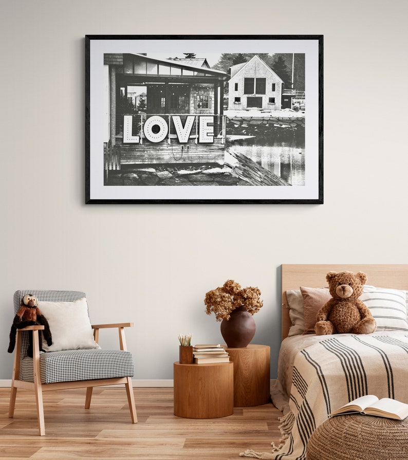 May include: Black and white photograph of a building with the word "LOVE" in large letters on the side. The photo is framed in a black frame and hanging on a white wall.