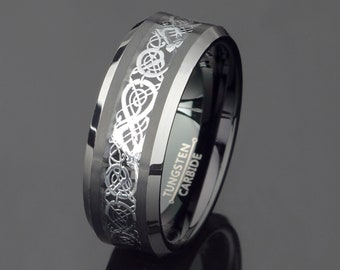 May include: A black tungsten carbide ring with a silver Celtic knot design. The ring is beveled and has the words "Tungsten Carbide" engraved on the side.