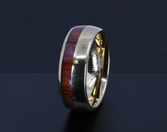 May include: A gold and silver ring with a brown wood inlay. The ring is a wedding band.