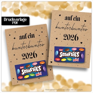 Puede incluir: Dos tarjetas marrones con el texto "auf ein kunterbuntes 2026" y una caja de caramelos Smarties Mini. Las tarjetas tienen decoraciones de estrellas y corazones negros. La tarjeta superior izquierda tiene el texto "Druckvorlage PDF".