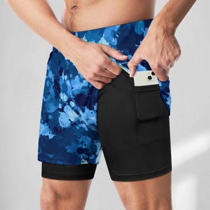 May include: Blue and black athletic shorts with a tie-dye pattern and a zippered pocket on the side.