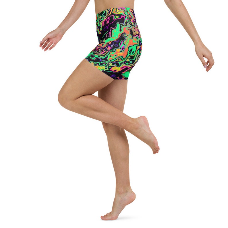 May include: A woman wearing black, green, pink, and yellow athletic shorts with a liquid swirl pattern. The shorts are high-waisted and have a stretchy fit.