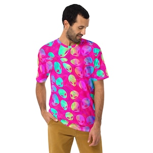 Puede incluir: Una camiseta rosa con un patrón repetido de caras de extraterrestres de colores. Las caras de los extraterrestres están delineadas en verde, azul y amarillo.